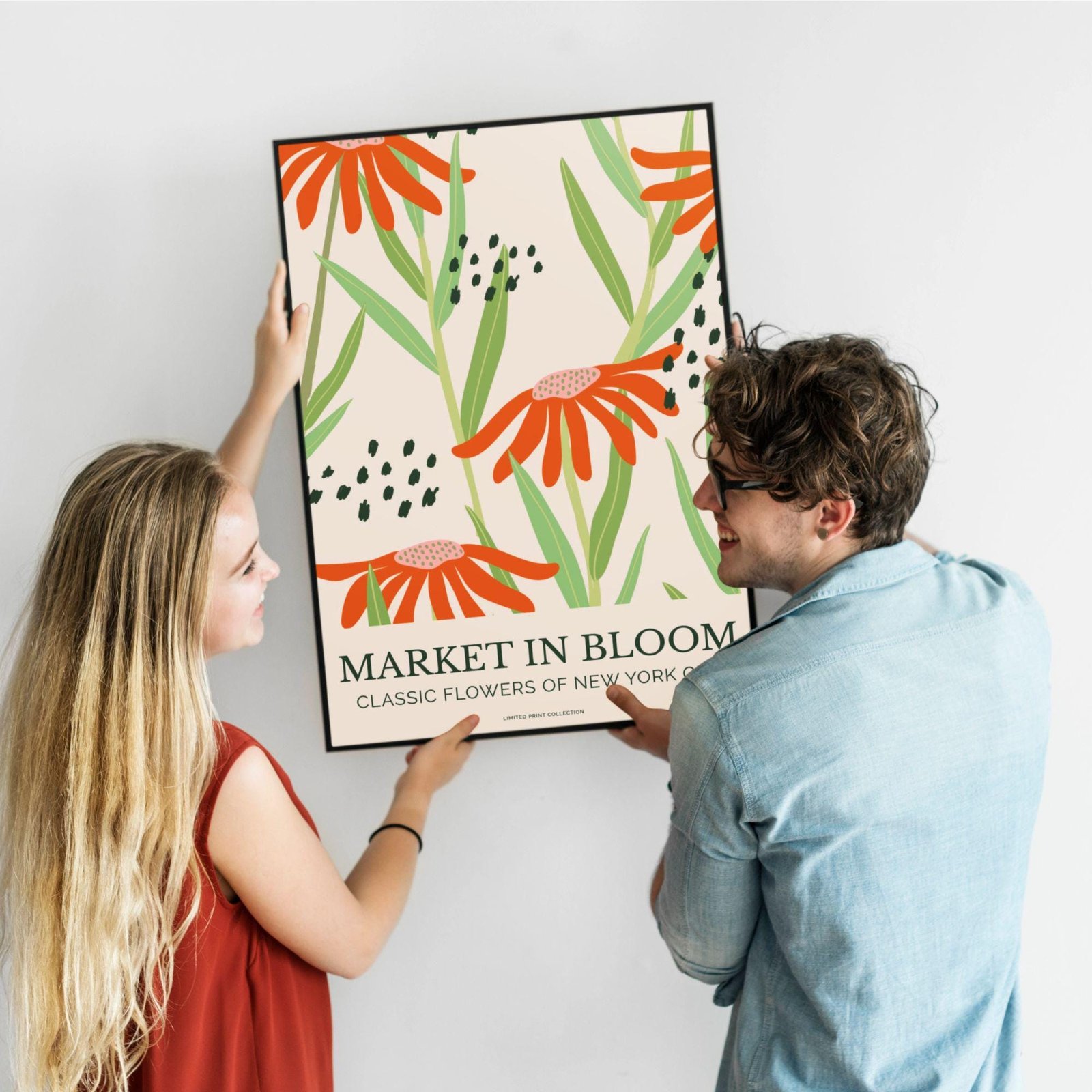 Two people hanging floral poster on wall.