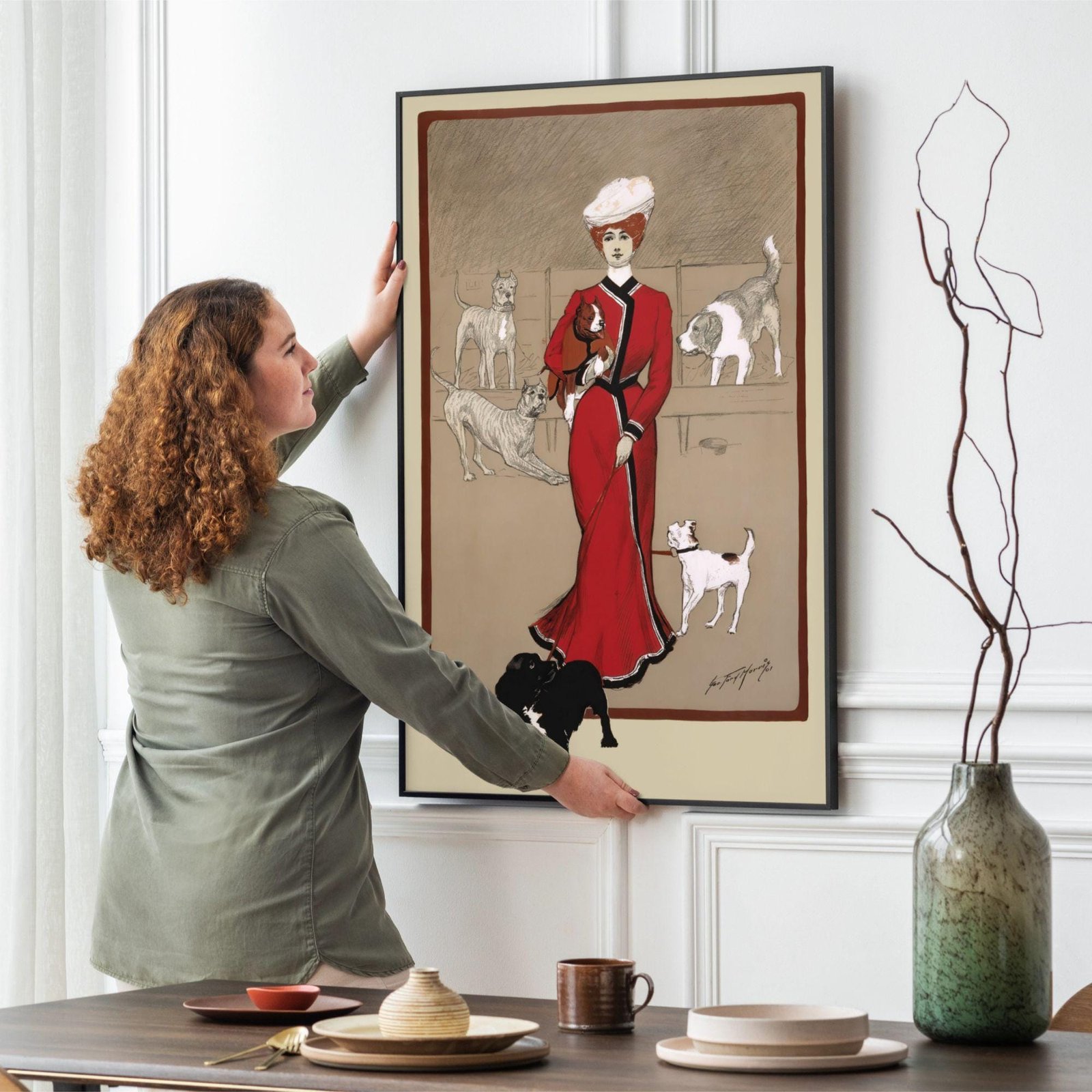Woman hanging artwork of lady with dogs