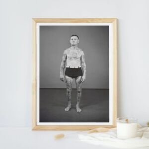 Framed photo of tattooed man in black shorts.