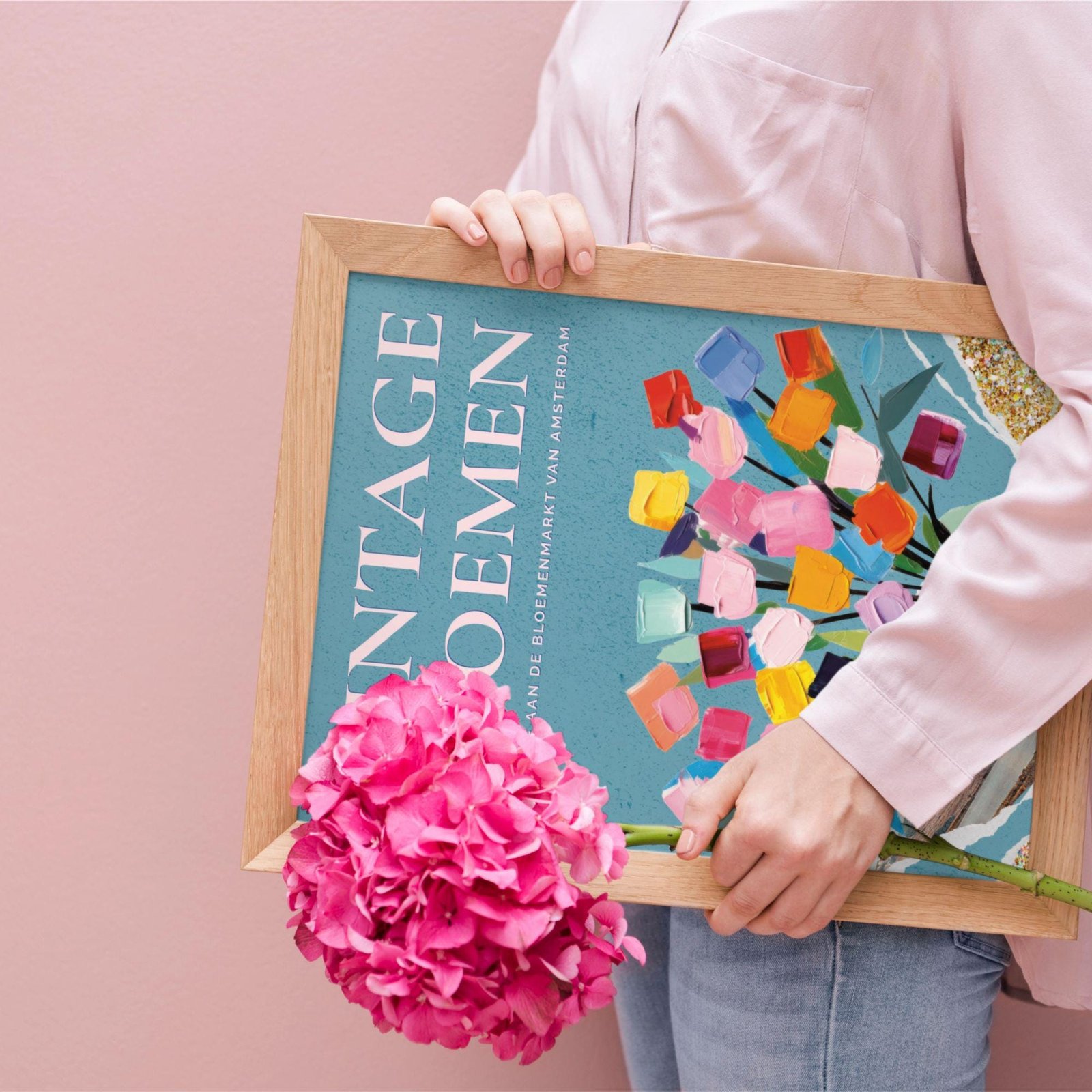 Woman holding colorful floral artwork and pink flowers.