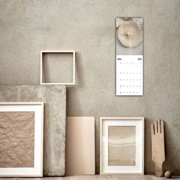 April 2027 wall calendar hung above neutral art frames
