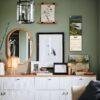 Stylish green wall gallery above white dresser with decor