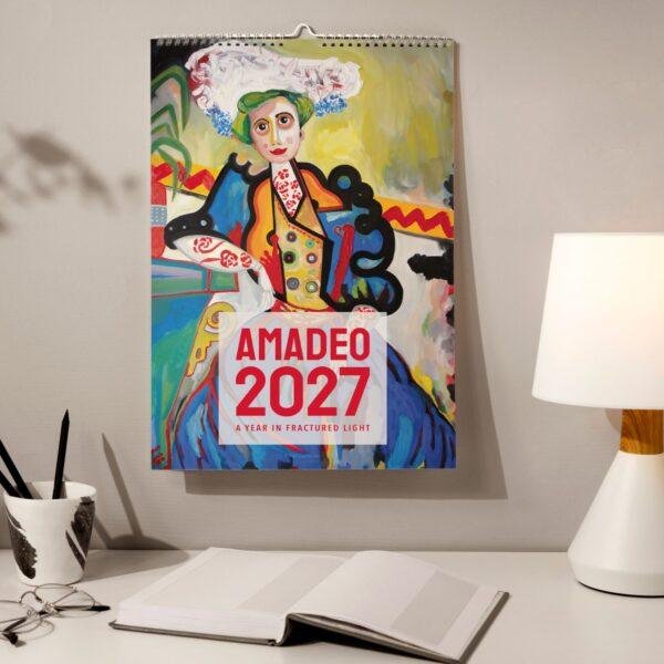 Amadeo 2027 art calendar hanging above a desk