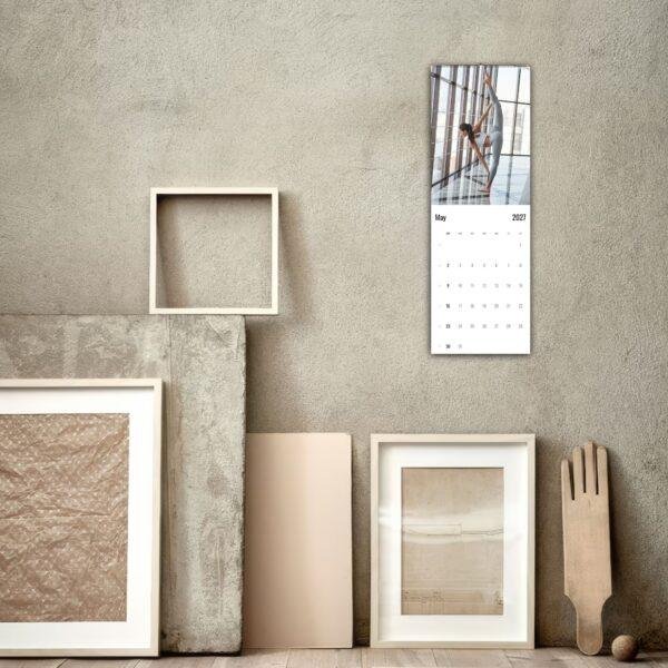 May 2027 yoga wall calendar hanging above rustic frames