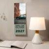 2027 Mini Car wall calendar hanging beside a desk lamp