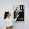 Woman touching framed Ella Fitzgerald poster on wall